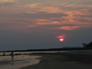 北海的住宿－银泰时光海景别墅酒店，日落时站在海滩上的人