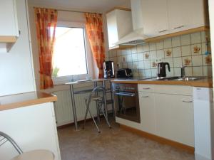 eine Küche mit weißen Schränken, einem Waschbecken und einem Fenster in der Unterkunft Ferienwohnung S und K Bremerhaven in Bremerhaven
