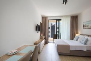 a bedroom with a bed and a table and a balcony at Apartments Djuro Rafailovic in Budva