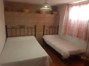 - 2 lits dans une petite chambre avec fenêtre dans l'établissement Casa Rural La Encina 2, à Lanjarón
