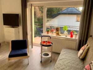 a living room with a chair and a table and a window at Apartament Leśny - Leśna 30 in Kudowa-Zdrój