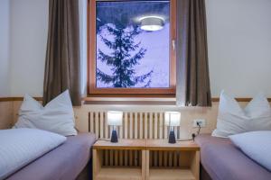 two beds in a room with two lamps on tables at Apt Emil - Haus Kostner in Santa Cristina Gherdëina