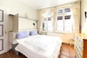 a bedroom with a white bed and two windows at Rosenstock Apartments Lüneburg in Lüneburg