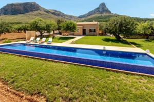 ein Schwimmbad in einem Garten mit Bergen im Hintergrund in der Unterkunft Finca can Jaumi By homevillas360 in Artá