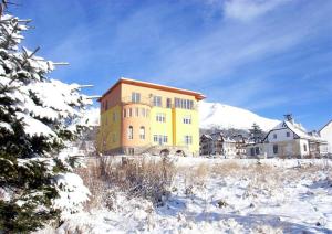 ein großes gelbes Gebäude auf einem schneebedeckten Feld in der Unterkunft Lydia in Vysoké Tatry