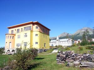 ein gelbes Gebäude auf einem Feld mit Bergen im Hintergrund in der Unterkunft Lydia in Vysoké Tatry
