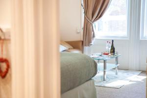 a room with a bed and a table with bottles of wine at Bournemouth apt for 2 Parking Walk to town & beach - Treeside Suite in Bournemouth