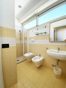 a bathroom with two sinks and a toilet and a window at Hotel Avana in Riccione