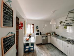 une cuisine avec des placards blancs et un tableau noir sur le mur dans l'établissement TEA HOUSE GERÊS, à Gerês