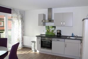 cocina con armarios blancos, fregadero y mesa en Königin Victoria - Appartement mit Saunanutzung, en Burgbernheim