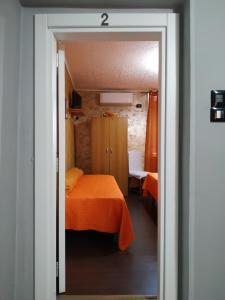 a bedroom with a bed with an orange blanket at B&B Arena Family in Fagnano Castello