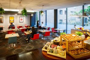 a restaurant with tables and chairs and people sitting at tables at Novotel Reading Centre in Reading