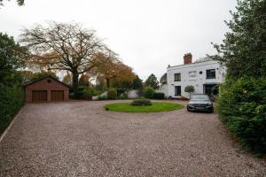 
a large white house with a large window at Luxury Coach house next to woodland in Knutsford in Knutsford

