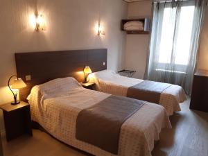 una camera d'albergo con due letti e due lampade di Logis Hotels - Hôtel Le Boulevard a Mazamet