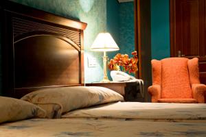 a bedroom with a bed and a chair and a lamp at Hotel Casona Los Caballeros in Santillana del Mar