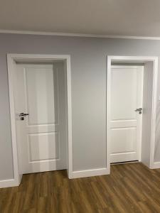 two doors in an empty room with wood floors at Domek Maris in Międzyzdroje