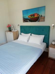a bed with a blue headboard and a picture of a boat at Casa Azul Hostel in Sintra