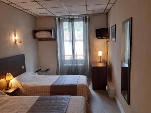 una camera d'albergo con due letti e una finestra di Logis Hotels - Hôtel Le Boulevard a Mazamet