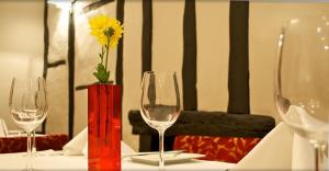 a table with two wine glasses and a yellow flower in a vase at The Tudor Hotel in Harrow