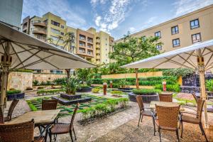 an outdoor patio with tables and chairs and umbrellas at City Lodge Hotel Umhlanga Ridge in Durban