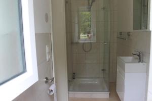 ein Bad mit einer Dusche und einem Waschbecken in der Unterkunft Zimmer am Waldeck in Langenargen