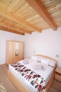 Cama grande en habitación con techo de madera en BONI Apartmanok en Hegykő