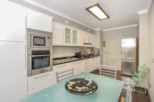 a kitchen with white cabinets and a table with a bowl on it at Apartamento Costa Do Sol in Funchal