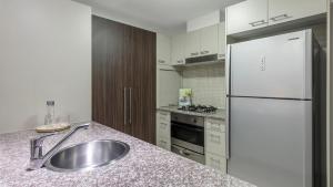a kitchen with a sink, stove and refrigerator at Oaks Brisbane Aurora Suites in Brisbane
