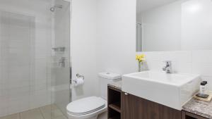 La salle de bains blanche est pourvue d'un lavabo et de toilettes. dans l'établissement Oaks Brisbane Aurora Suites, à Brisbane