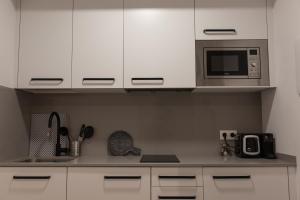 a kitchen with white cabinets and a microwave at Loft en Zarautz con Parking Hator 2 in Zarautz
