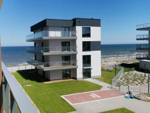 a building on the beach with the ocean in the background at Apartament Gardenia Klif 35 z widokiem na morze in Dziwnów