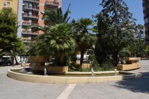 une fontaine dans un parc avec des palmiers et un bâtiment dans l'établissement HYGGE Apartment Short Lets, à Tarente
