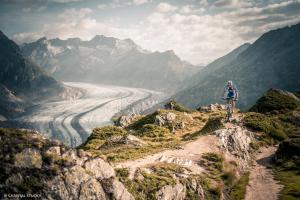 Ein Mann, der auf einem Bergpfad mit Blick auf einen Fluss Fahrrad fährt in der Unterkunft Sport Resort Fiesch, Garni Goneri in Fiesch