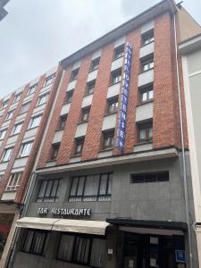 a tall red brick building with a blue sign on it at Hotel Ovetense in Oviedo