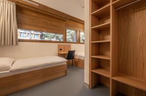 ein Schlafzimmer mit einem Bett, einem Fenster und Regalen in der Unterkunft Sport Resort Fiesch, Garni Goneri in Fiesch + 11 Fotos
