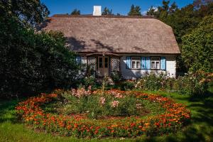 Cette petite maison dispose d'un toit de chaume et d'un jardin fleuri. dans l'établissement Siedlisko olenderskie na Mazowszu, à Łady