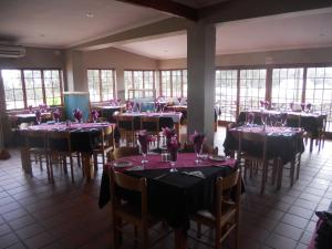 a restaurant with tables and chairs with purple flowers on them at Juffroushoogte Gaste Plaas in Vredenburg