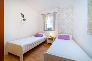 2 camas en una habitación pequeña con ventana en Apartments Milka, en Povljana