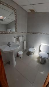 y baño con lavabo, aseo y espejo. en Hostal Restaurante Pinarejo, en A Lanzada