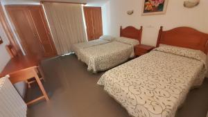 een slaapkamer met 2 bedden en een tafel bij Hostal Restaurante Pinarejo in A Lanzada