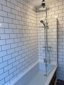 uma casa de banho em azulejos brancos com uma banheira e um chuveiro em Withens Way Holiday Cottage, 2 Bedrooms, Haworth em Haworth