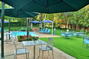 a group of tables and chairs with umbrellas next to a pool at Town Lodge Menlo Park in Pretoria
