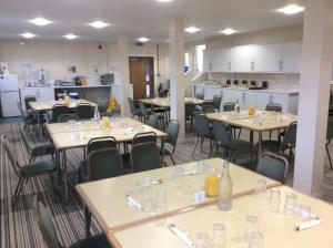 a room with tables and chairs and a kitchen at FSC Millport Hostel in Millport
