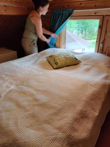 a woman is standing next to a large bed at Kaijonselän mökit Kaita in Kaitainen