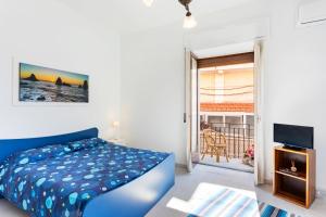- une chambre avec un lit bleu et un balcon dans l'établissement La Finestra dei Ciclopi, à Aci Castello