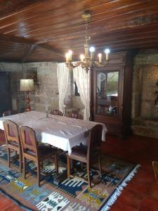 uma sala de jantar com uma mesa com cadeiras e um lustre em Casa Dos Gaios em Vieira do Minho