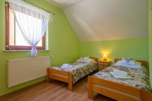 a green room with two beds and a window at Dom Myśliwski in Szklarska Poręba