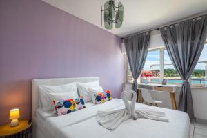 una camera con due letti con pareti viola e una finestra di Apartments Villa Zrinka a Rogoznica (Rogosnizza)
