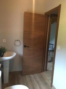 Łazienka z drewnianymi drzwiami obok umywalki w obiekcie Casita Junto al Río Deva w mieście Vilde