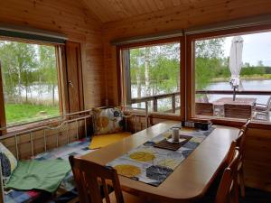 a dining room with a table and two windows at Kaijonselän mökit Kaita in Kaitainen